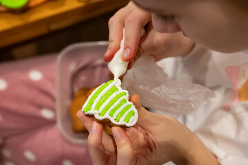 Cookie decorating activity featuring a person applying green icing in a cozy indoor setting during...