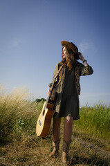 A girl with a guitar in cowboy style. Cowboy hat and boots. Sunny atmospheric photos.