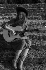 A girl with a guitar in cowboy style. Cowboy hat and boots. Sunny atmospheric photos.