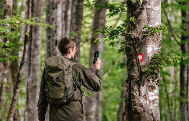 Man Walking in Forest Taking Picture with Phone