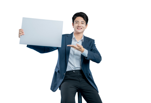 A young Asian businessman sits on a stool, presenting a blank white sign with an open palm gesture for your message or advertisement.
