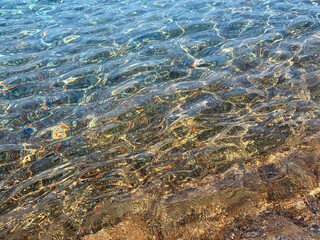 Clean sea water with colorful pebbles at the bottom