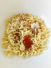 Cooked instant noodles topped with seasoning sauce and dried toppings, not mixed yet