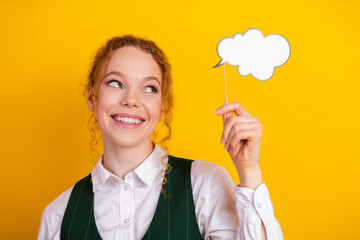 Happy teen girl with curly hair holding thought bubble on yellow background, expressing ideas and...