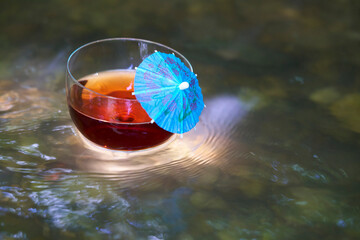 Roter Saft mit blauem Sonnenschirmchen im Wasser