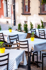 Outdoor empty Cafe seating. Chairs and tables. Old tourist town in summer street bar patio. Tablecloth