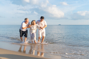 Family On Summer Beach Vacation, Father and mather running with son, Concept for 
caring for the elderly, Caregiving to older persons and relations of the family to support elderly state