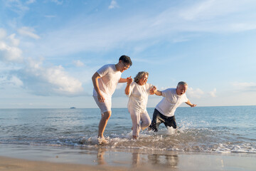 Family On Summer Beach Vacation, Father and mather running with son, Concept for 
caring for the elderly, Caregiving to older persons and relations of the family to support elderly state