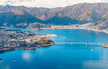 Naklejka premium A sweeping aerial view of Lake Kawaguchiko with Mount Fuji rising in the distance, revealing a breathtaking perspective of Japan’s iconic landscape. 