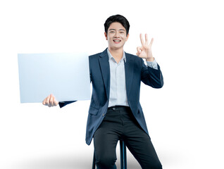 A happy Asian businessman holds a blank sign and makes an 