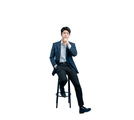young businessman sits on a stool looking upwards, with his hand on his chin as he considers a...