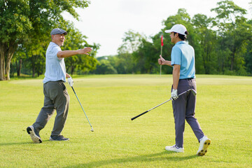 Asian man and elderly father are enjoy playing golf together with a good time.