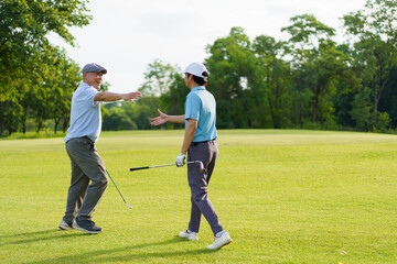 Asian man and elderly father are enjoy playing golf together with a good time.