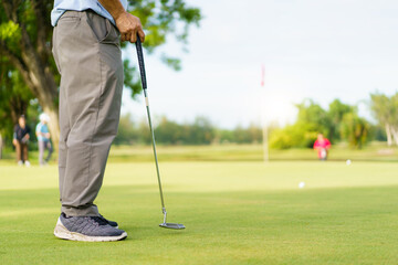 Fototapeta premium Elderly Asian man enjoying the morning round of golf in soft and warm sunlight.