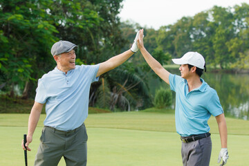 Asian man and elderly father are enjoy playing golf together with a good time.