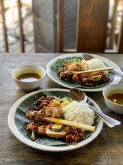 Nasi Campur is a Traditional Balinese rice dish served on a banana leaf with various side dishes,...