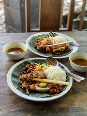 Nasi Campur is a Traditional Balinese rice dish served on a banana leaf with various side dishes, showcasing authentic Indonesian cuisine.