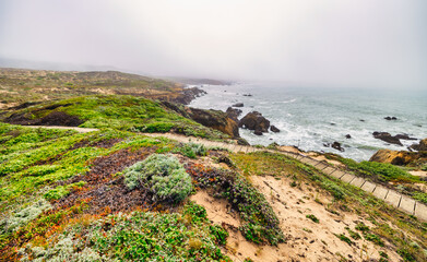Coastal bench view at the edge of the Pacific along Highway 1 in California, surrounded by lush...