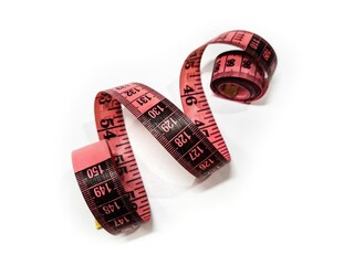 Pink measuring tape on a white background. Centimeter and inch tools for measuring the length or volume of the human body in the clothing industry.