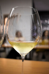 Crystal clear glass filled with chilled white wine in tasting room