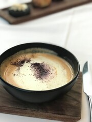Creamy Gourmet Soup in Black Bowl on Wooden Board