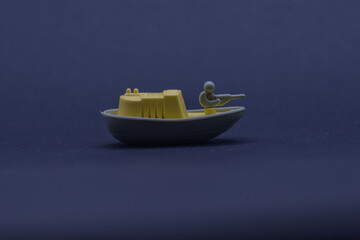 Yellow toy boat floating on dark blue water, ideal for childrens books, summerthemed designs,...