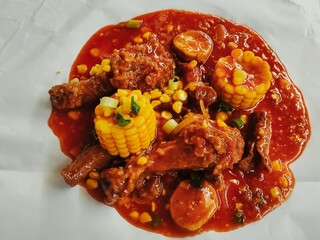 Close-up of crispy fried chicken topped with Asian sweet and spicy sauce. Added with sweet corn, sausage, and spring onion.