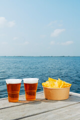 cups with beer and some potato chips on a dock