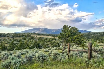 Landscape of distant mountains beyond a fence and rolling green hills on an overcast Summer day...