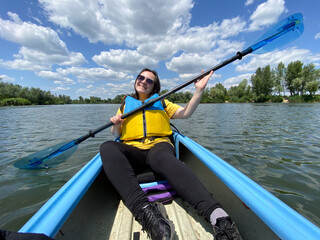 Happy woman in kayak with paddle, summer day, kayaking on the river.