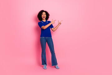 Adorable woman wearing casual blue polo and jeans pointing excitedly against a pink background showcasing modern fashion