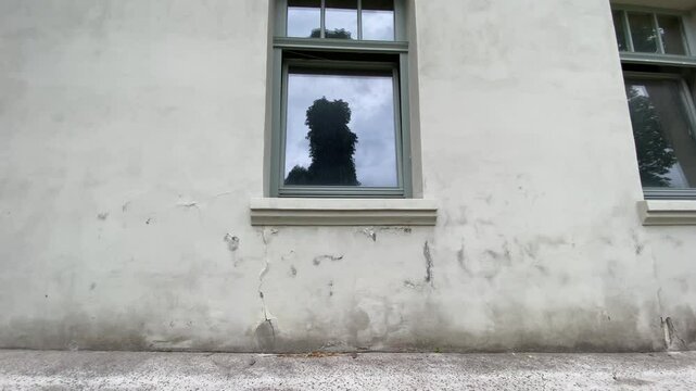 Damaged house wall with vertical cracks, peeling paint, and signs of water infiltration