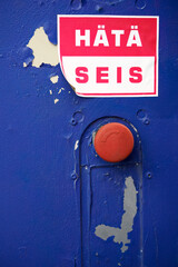 Red push button with a Finnish emergency stop sticker