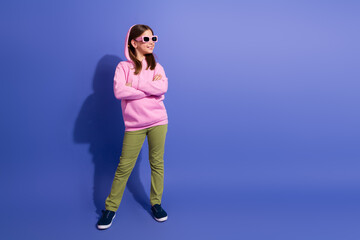 Smiling schoolgirl in bright hoodie demonstrates youthful style against vibrant violet background