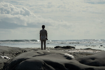 A man stands on a secluded tropical beach. A man enjoys the beauty of a tropical Indonesian beach on a sunny day