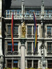 The golden ST Mary's column in Marienplatz against the New Town Hall in gothic style decorated by the LGBT flags