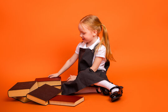 Adorable little girl sitting with books on an orange background showing a curious and happy expression - Powered by Adobe