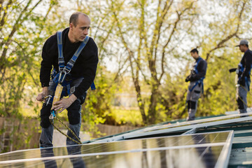 Technicians installing solar panels on residential house roof