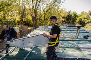 Workers installing solar panel on a roof
