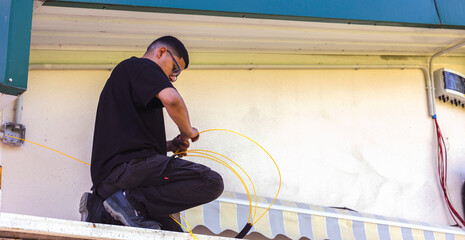 Technician installing fiber optic cable on building exterior