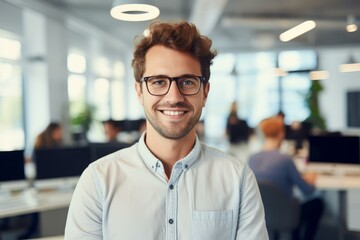 Naklejka na ściany i meble Portrait of a smiling businessman wearing eyeglasses in a modern office, his colleagues working in the background