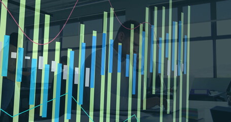 In office, man working on laptop with financial data graphs overlaying screen
