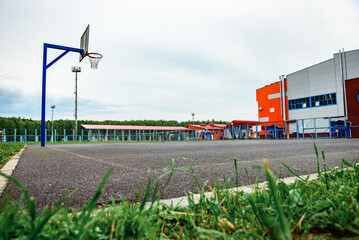 Outdoor basketball court with a metal hoop and fencing under blue sky.
