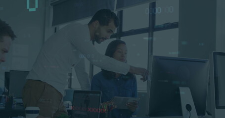 Collaborating coworkers pointing at monitor in modern open workspace, with laptop and tablet