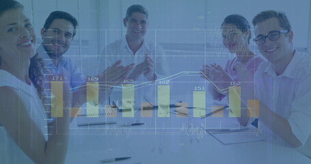 Clapping business professionals in suits at meeting room table, with pens and digital chart overlay