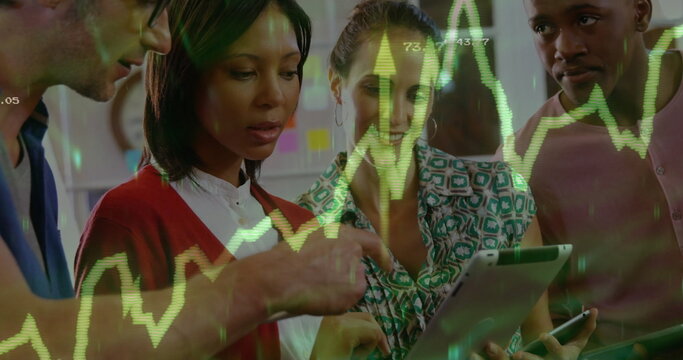 Reviewing green stock chart on tablet and phone by four colleagues in office space, sticky notes