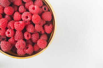Ripe pink raspberries in a ceramic bowl on a white background. Summer berry harvest concept....