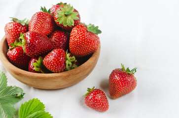 Ripe red strawberries in a ceramic bowl on a white background. Concept of summer berry harvest. Horizontal orientation. Selective focus. Copy space.
