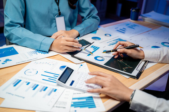 Businesswomen are discussing company's financial reports using charts, graphs, and calculator during a meeting