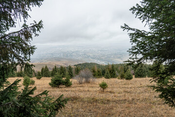 Distant view of Kyrgyz town Karakol from the nearby Tian Shan slopes covered with golden grass in...